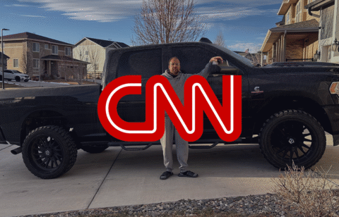 Person standing beside a large black pickup truck in a suburban driveway, with a red CNN logo overlaid on the image.