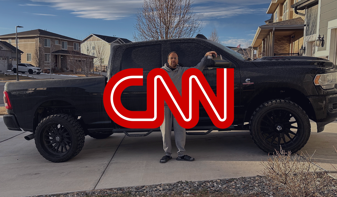 Person standing beside a large black pickup truck in a suburban driveway, with a red CNN logo overlaid on the image.