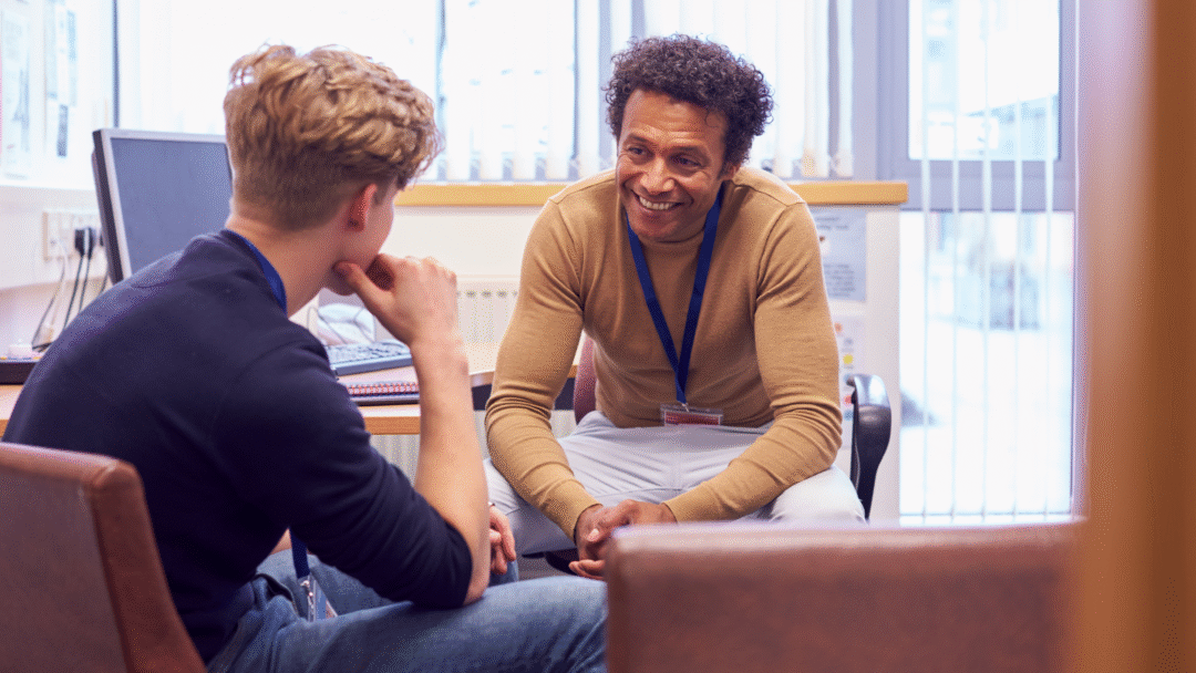 A professional meeting between two individuals in a small office, engaged in a focused and friendly conversation.