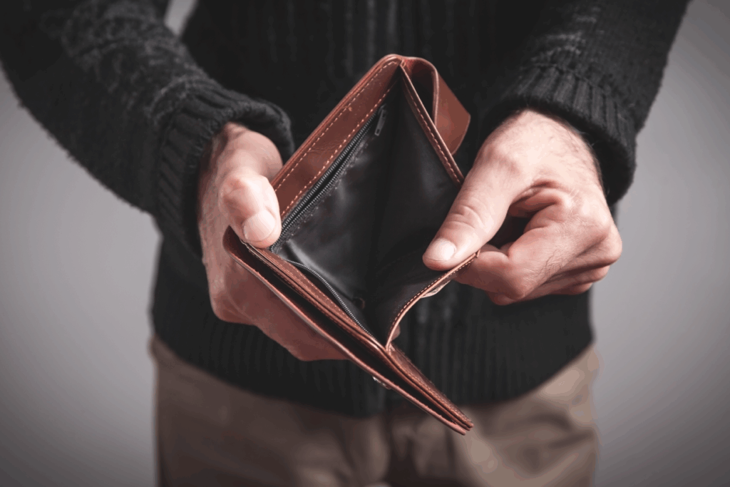 Person holding an open, empty wallet with no cash inside.