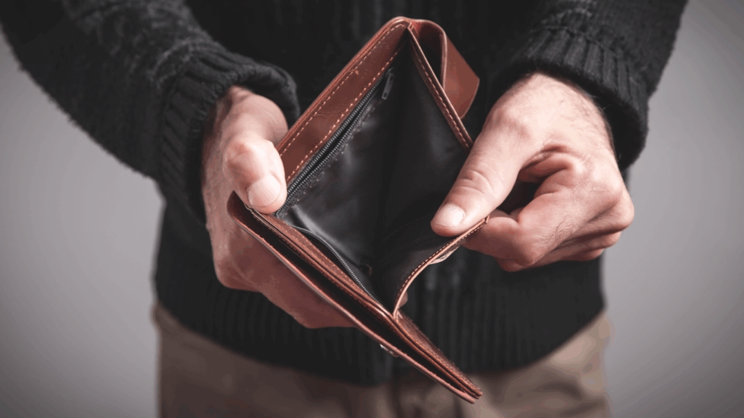 Person holding an open, empty wallet with no cash inside.