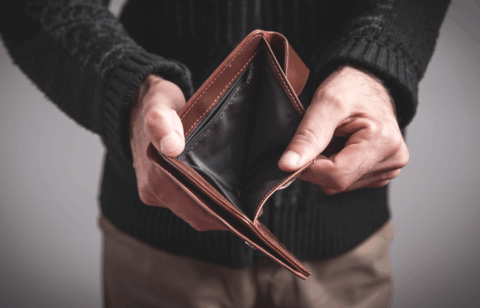 Person holding an open, empty wallet with no cash inside.