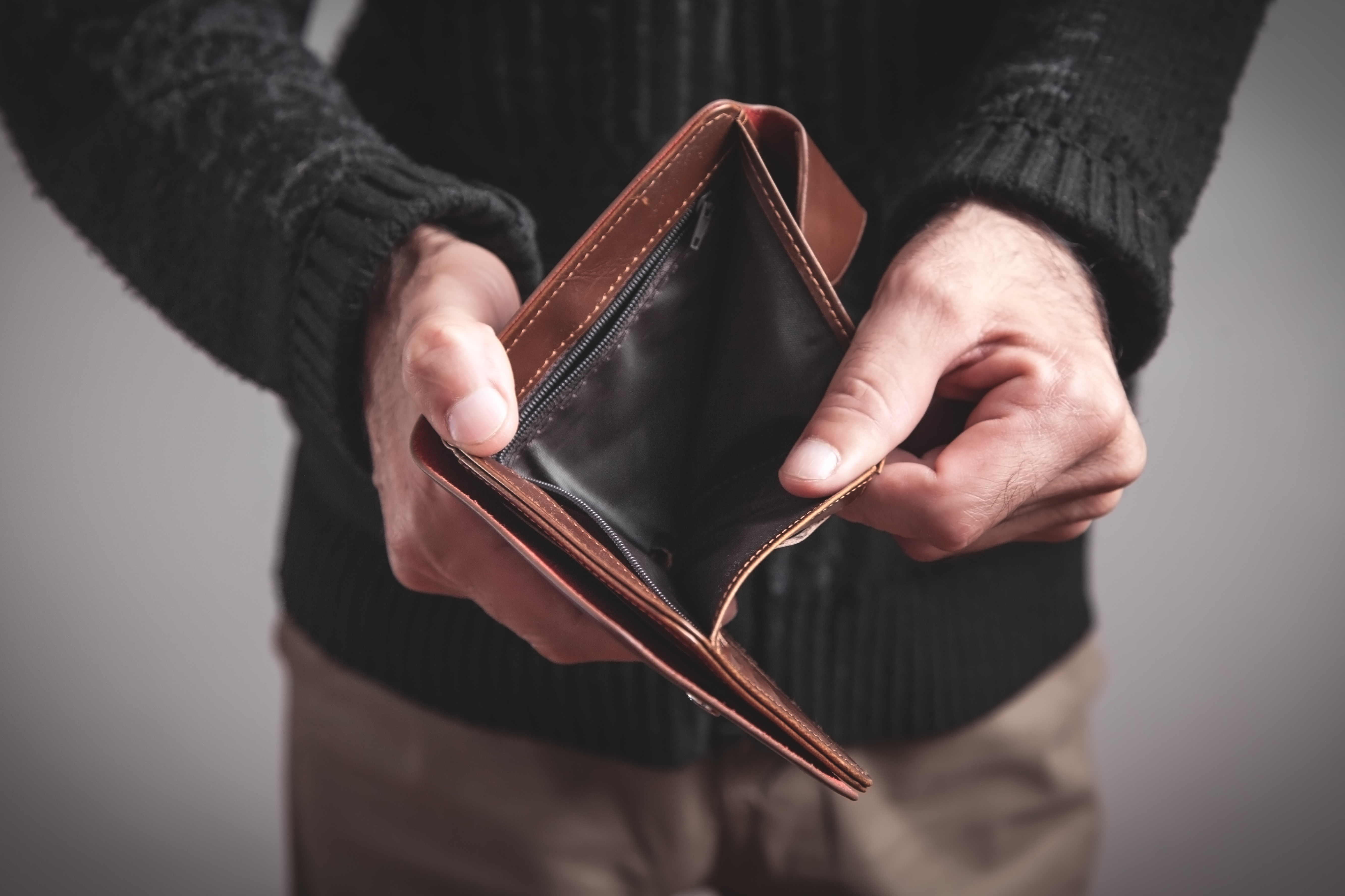 Person holding an open, empty wallet with no cash inside.