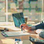 Person stamping a document at a desk with car keys, a calculator, and a laptop nearby.