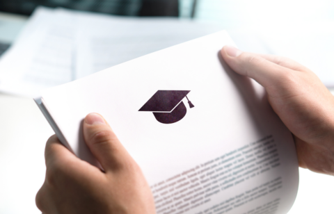 Hands holding a document with a graduation cap icon, representing student loan or education-related paperwork
