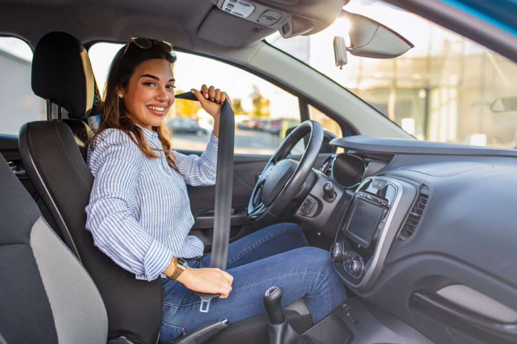 Woman sitting in the driver’s seat fastening her seatbelt inside a car