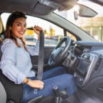 Woman sitting in the driver’s seat fastening her seatbelt inside a car