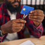 Person using scissors to cut a credit card while sitting at a desk.