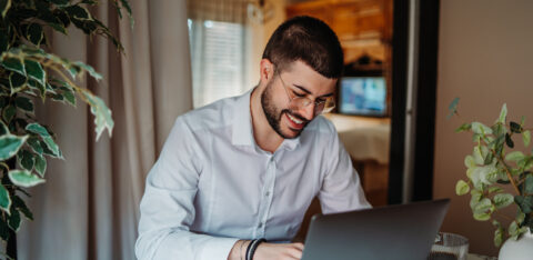 Young man happily working from home using laptop