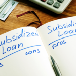 Notebook comparing unsubsidized and subsidized loans with pros and cons, next to cash and a calculator