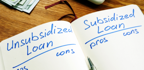 Notebook comparing unsubsidized and subsidized loans with pros and cons, next to cash and a calculator
