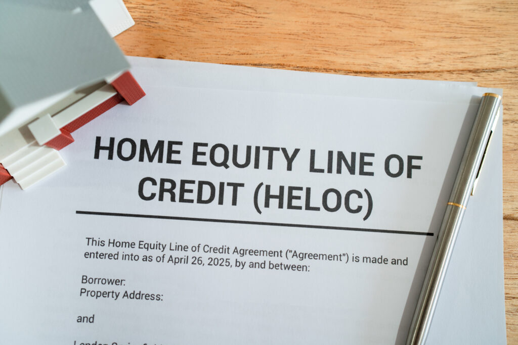 Document titled “Home Equity Line of Credit (HELOC)” on a desk with a pen and small house model nearby.