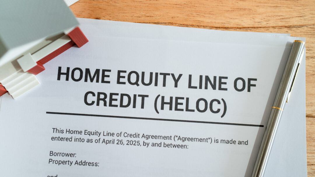 Document titled “Home Equity Line of Credit (HELOC)” on a desk with a pen and small house model nearby.