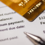 Close-up of a credit card resting on a billing statement showing a new balance, minimum payment, and due date.