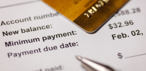 Close-up of a credit card resting on a billing statement showing a new balance, minimum payment, and due date.