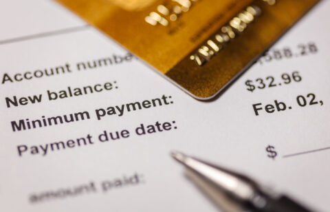 Close-up of a credit card resting on a billing statement showing a new balance, minimum payment, and due date.