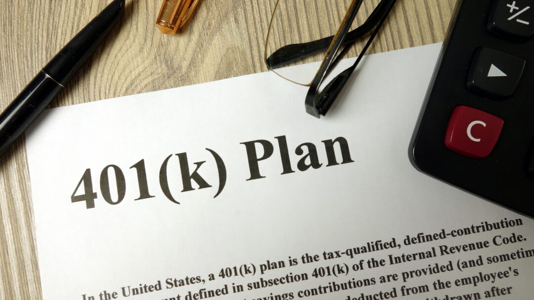 Document labeled “401(k) Plan” on a desk with a pen, eyeglasses, and calculator nearby.