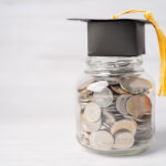 Jar of mixed coins with a black graduation cap and tassel on top