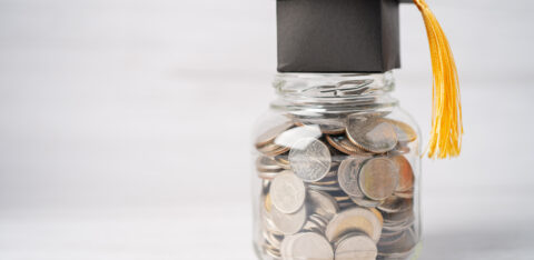 Jar of mixed coins with a black graduation cap and tassel on top