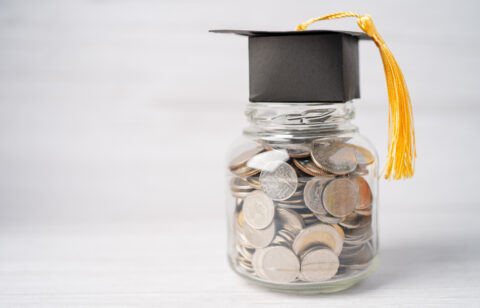 Jar of mixed coins with a black graduation cap and tassel on top
