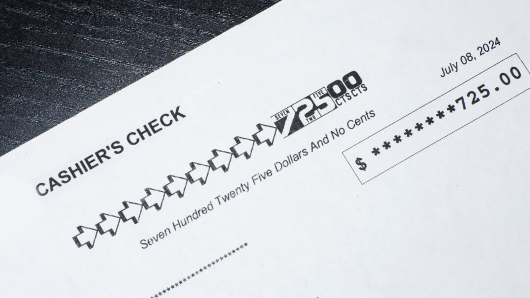 Close-up of a cashier’s check showing a payment amount of $725 with the date printed.