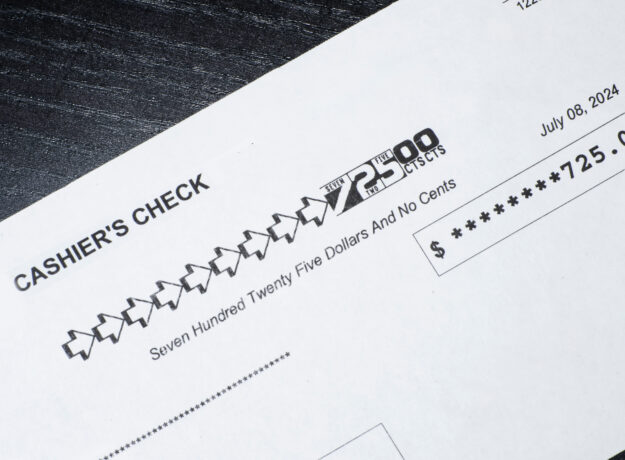 Close-up of a cashier’s check showing a payment amount of $725 with the date printed.