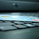 Credit card placed across computer keys, with a blurred laptop screen in the background.