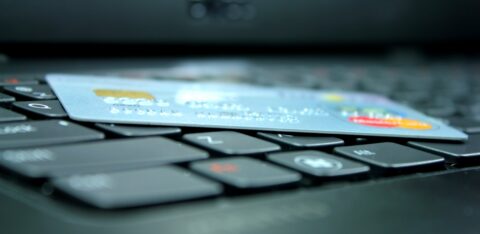 Credit card placed across computer keys, with a blurred laptop screen in the background.