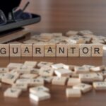 Wooden letter tiles spelling “guarantor” on a table, with scattered tiles and books in the background.