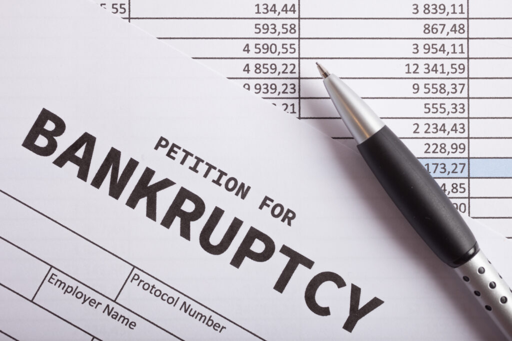 Close-up of a document labeled “petition for bankruptcy” with a pen resting on financial statements