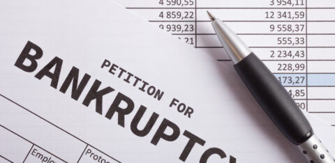 Close-up of a document labeled “petition for bankruptcy” with a pen resting on financial statements