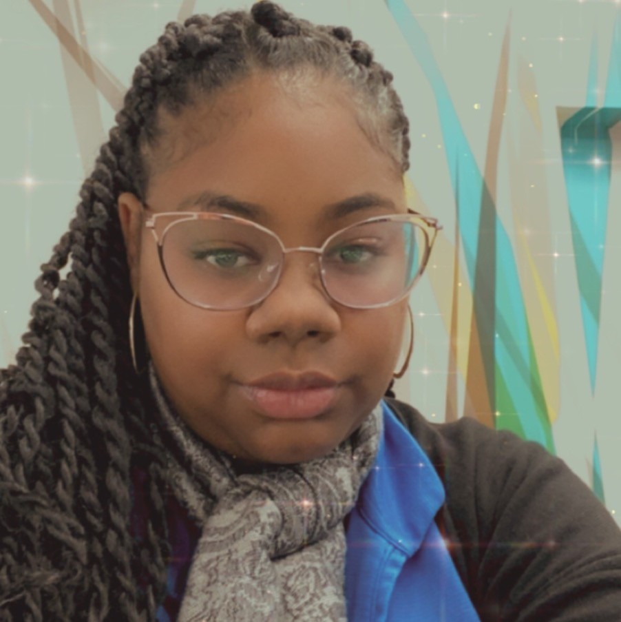 Woman with braided hair and glasses taking a selfie indoors, wearing a scarf and blue shirt