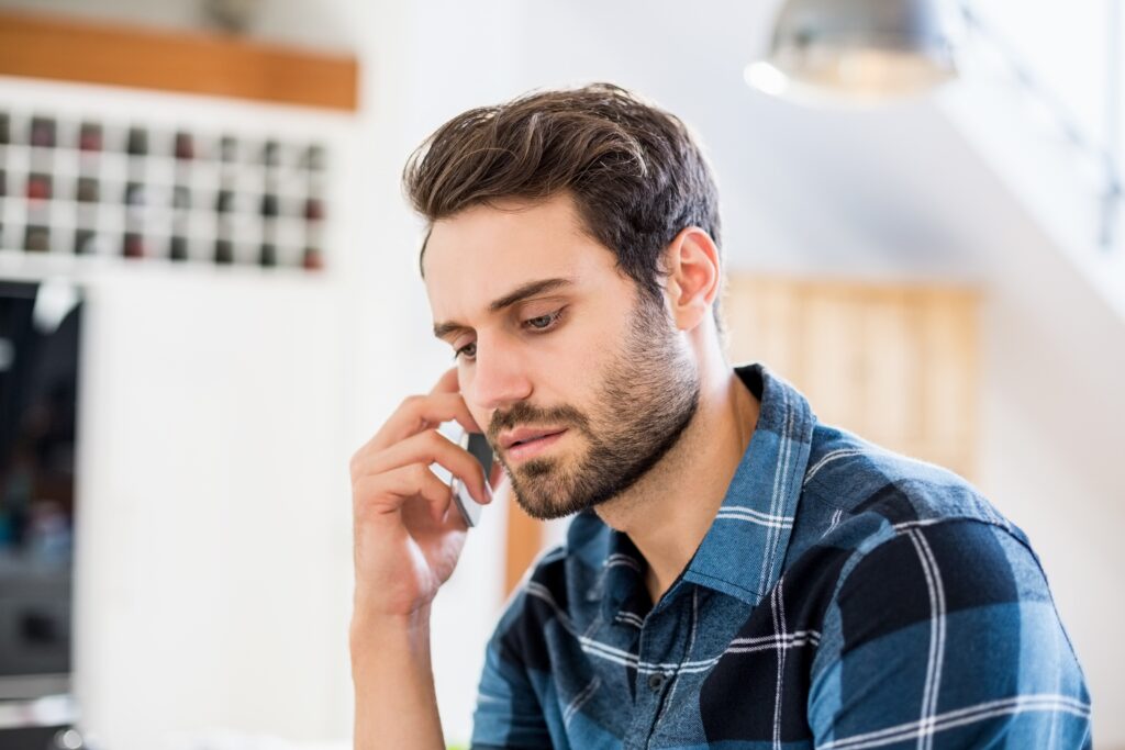 Person talking on a smartphone with a serious expression while seated indoors