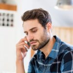 Person talking on a smartphone with a serious expression while seated indoors