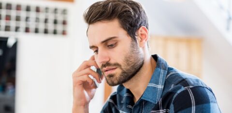 Person talking on a smartphone with a serious expression while seated indoors