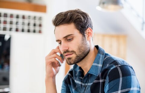 Person talking on a smartphone with a serious expression while seated indoors