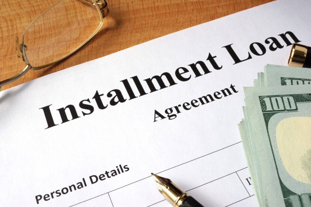 Close-up of an installment loan agreement document with cash, a pen, and eyeglasses on a desk