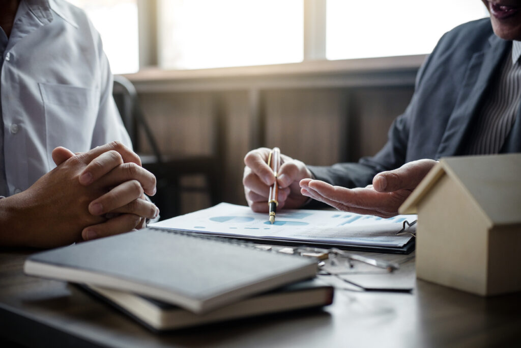 Two people reviewing financial documents at a desk, with one person pointing to a chart on a report.
