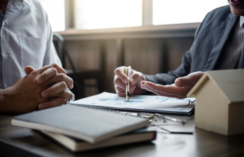 Two people reviewing financial documents at a desk, with one person pointing to a chart on a report.