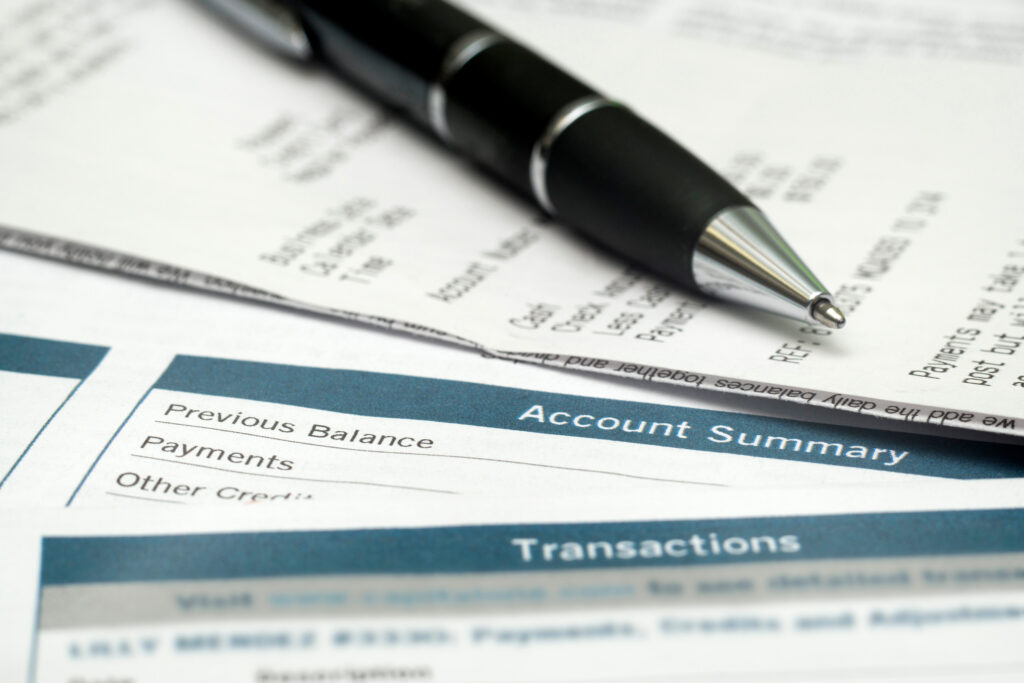 Close-up of a billing statement with an account summary section and a pen resting on top