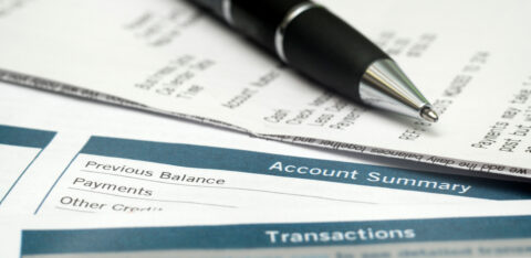 Close-up of a billing statement with an account summary section and a pen resting on top