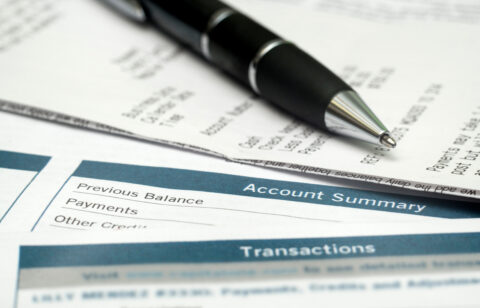 Close-up of a billing statement with an account summary section and a pen resting on top