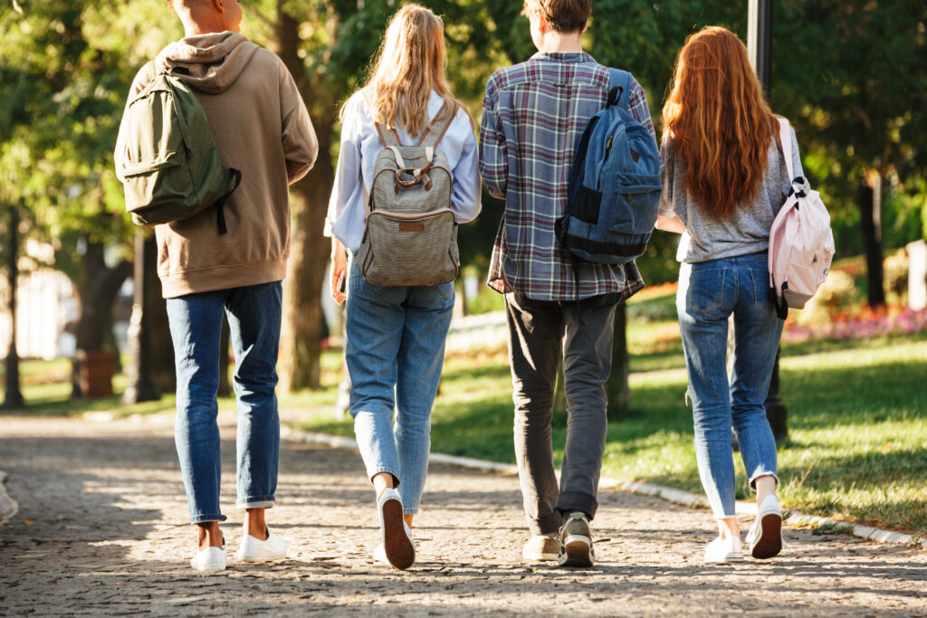 Group of college-age students walking across campus with backpacks between classes.