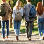 Group of college-age students walking across campus with backpacks between classes.