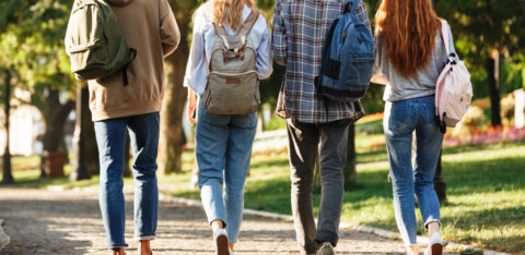Group of college-age students walking across campus with backpacks between classes.