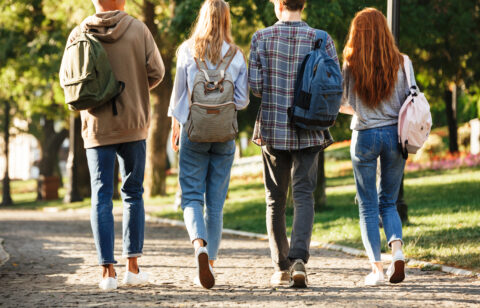 Group of college-age students walking across campus with backpacks between classes.