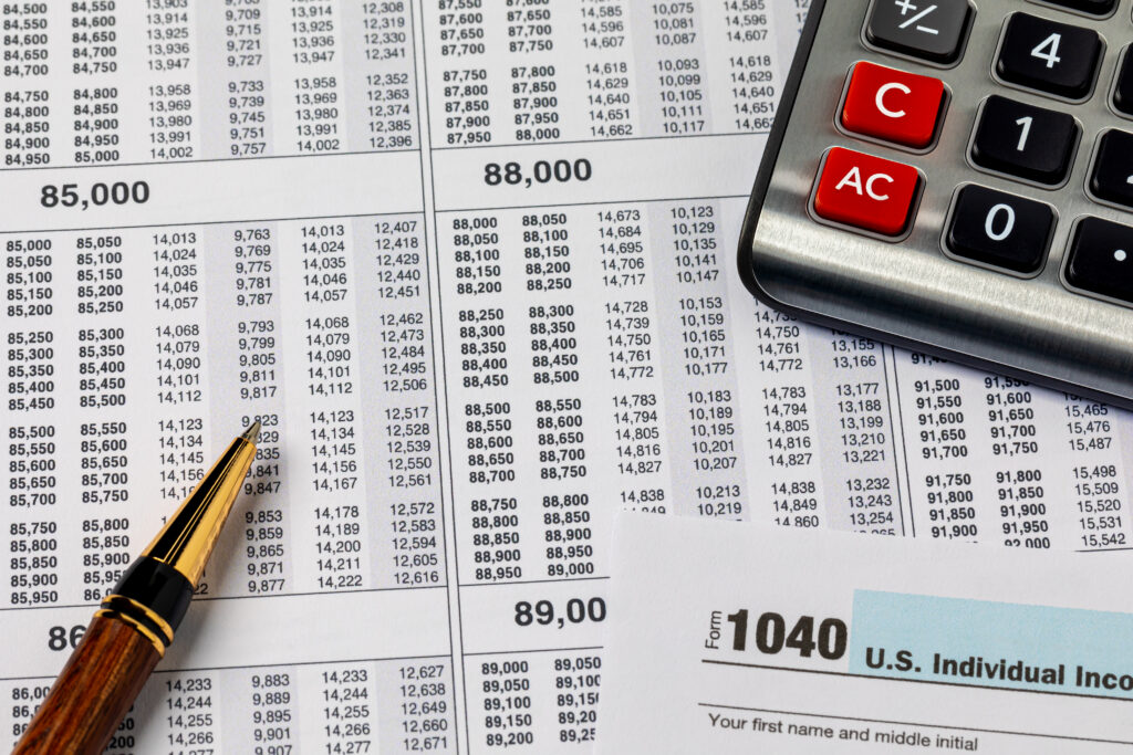 Close-up of tax documents with a calculator and pen, including a visible IRS Form 1040