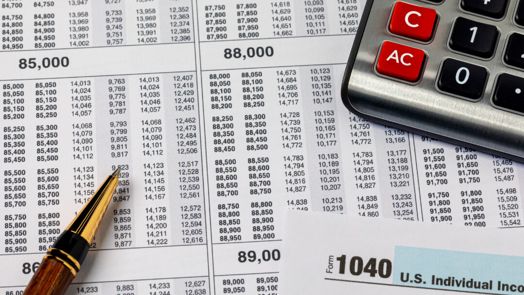 Close-up of tax documents with a calculator and pen, including a visible IRS Form 1040