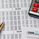 Close-up of tax documents with a calculator and pen, including a visible IRS Form 1040