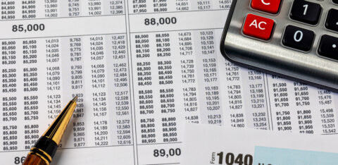 Close-up of tax documents with a calculator and pen, including a visible IRS Form 1040